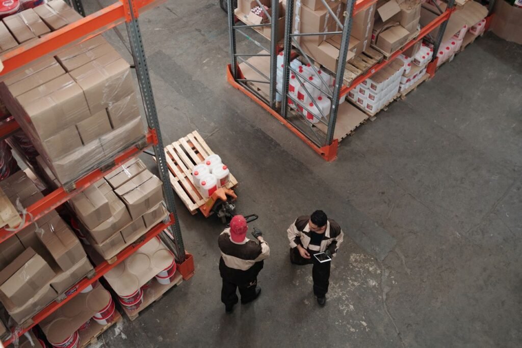 Warehouse workers moving stock between shelves of boxes