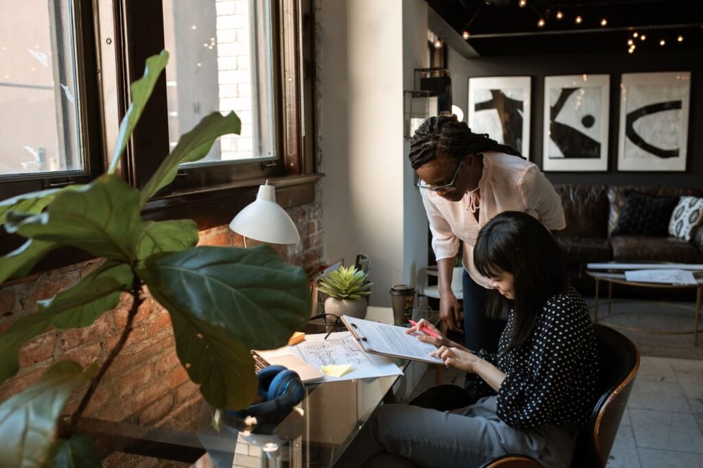 Two women reviewing printed documents at a desk