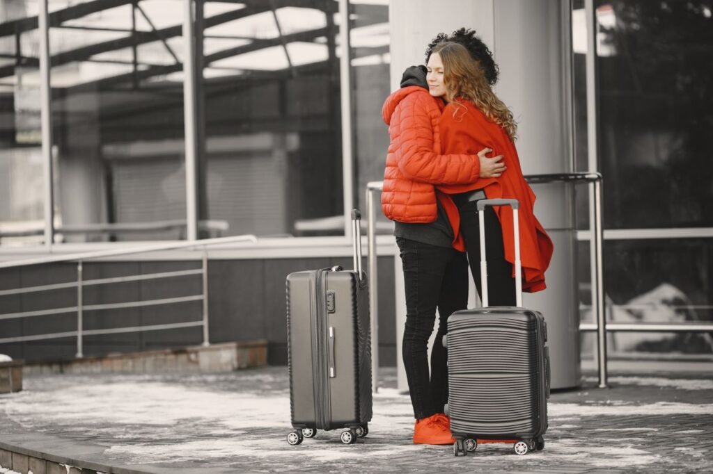 Two people hugging goodbye at an airport with luggage