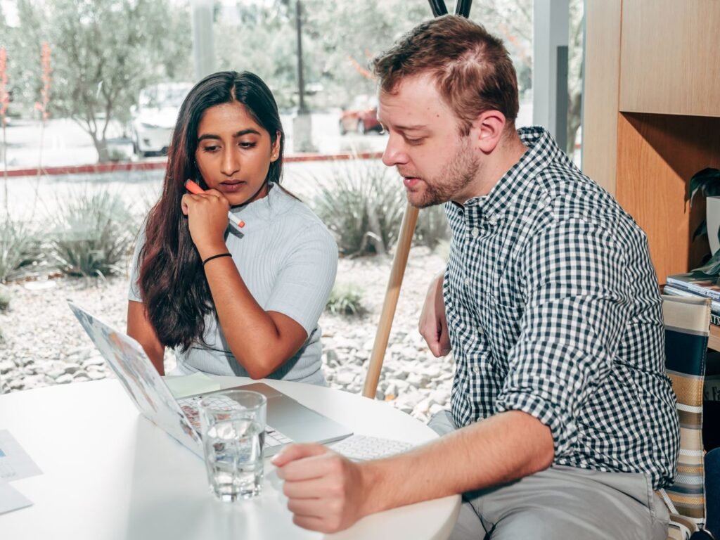 South Asian woman and white man comparing options at a laptop